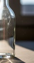 An empty glass bottle standing on a table in sunlight, with details of dust and reflections adding to the texture. Royalty Free Stock Photo
