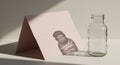 Clear glass bottle positioned on a white surface next to a pink folded card. The card Royalty Free Stock Photo