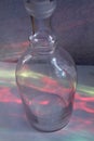 Clear glass bottle with rainbow like reflections of other colored bottles  red, green, yellow, blue Royalty Free Stock Photo