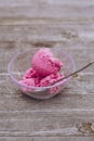 Clear glass bowl of delicious strawberry ice-cream and a spoon on a wooden surface Royalty Free Stock Photo