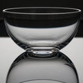 A clear glass bowl with smooth contours sits atop a reflective surface, creating a Royalty Free Stock Photo
