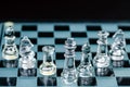 Transparent glass chess pieces arranged in a row reflecting in glass chessboard. Isolated on black Royalty Free Stock Photo