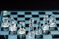 Transparent glass chess pieces arranged in a row reflecting in glass chessboard. Isolated on black Royalty Free Stock Photo