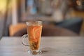 Clear glass cup of tea on table in cafe interior with blurred color background