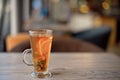 Clear glass cup of tea on table in cafe interior with blurred color background