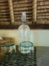 Clear glass cups and a glass bottle placed in a tropical villa setting Royalty Free Stock Photo
