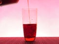 In a clear glass filled with a dark fizzy drink. Photo on a pink background Royalty Free Stock Photo