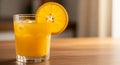 A clear glass filled with orange juice rests on a wooden surface. Ice cubes are visible Royalty Free Stock Photo
