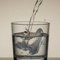 Clear glass filled with water from a gentle stream, causing splashes and bubbles. Clos Royalty Free Stock Photo