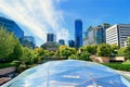 Clear glass greenhouse with trees in the foreground and a city skyline in the