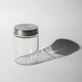 A clear glass jar with a silver metal lid stands on a white surface Royalty Free Stock Photo