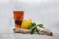 Clear glass mug filled with steaming hot tea with a lemon and ginger atop a white table Royalty Free Stock Photo