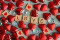 Red heart shapes and clear glass word love on wooden background