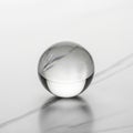 Clear glass sphere resting on a smooth, light-gray marble surface with faint veining. Royalty Free Stock Photo