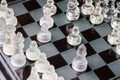 Glass, transparent chess pieces on a checkerboard, selective focus, close-up, isolated on black Royalty Free Stock Photo