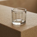 A clear glass tumbler with a thick base is placed on a textured, beige stone-like Royalty Free Stock Photo