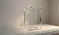 clear glass vase with rectangular base sits on white surface, casting shadow and illuminated by light source. Royalty Free Stock Photo