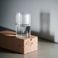 A clear glass of water is balanced on a light brown clay brick Royalty Free Stock Photo