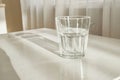 Clear glass of clear water on minimalist table with window light and shadow Royalty Free Stock Photo