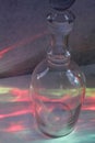 Clear glass wine decanter with reflections of multicolored bottles