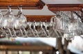 Clear glasses hanging on wooden shelf in bar. Empty wineglasses. Alcohol and drink concept. Pub interior.