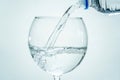 Clear healthy sparkling water is poured from a bottle into a transparent glass on a white background. Closeup Royalty Free Stock Photo