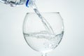 Clear healthy sparkling water is poured from a bottle into a transparent glass on a white background. Closeup Royalty Free Stock Photo