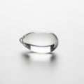 A clear liquid drop sits on a smooth white surface casting a soft shadow Royalty Free Stock Photo