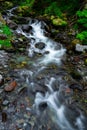 \'Clear mountain stream flowing over smooth rocks, long exposure silky water effect, surrounded by moss and greenery\' Royalty Free Stock Photo