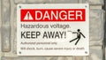 Clear Panorama Close up of Danger Hazardous Voltage Keep Away sign posted on a gray surface