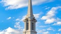 Clear Panorama Exterior of a beautiful church with a white steeple against cloudy blue sky Royalty Free Stock Photo