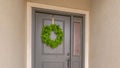 Clear Panorama Gray front door of a home with a simple green wreath and sidelight