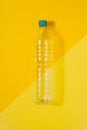 Clear plastic bottle with blue cap on a yellow background. Recycling and environment concept Royalty Free Stock Photo