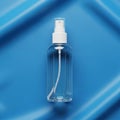 Clear plastic spray bottle with a white cap and nozzle on a smooth blue Royalty Free Stock Photo
