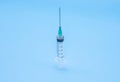 Clear plastic syringe with needle isolated against a blue background