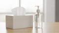 Clear pump bottle of hand sanitizer and box of tissues on wooden surface with bright soft focus background Royalty Free Stock Photo