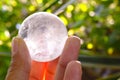 Clear quartz crystal sphere ball with rainbow colour inside it in hand on nature background. Royalty Free Stock Photo