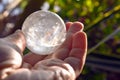 Clear quartz crystal sphere ball with rainbow colour inside it in hand on nature background. Royalty Free Stock Photo