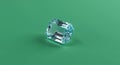 A clear, rectangular-cut aquamarine gemstone rests on a solid green surface. The ge Royalty Free Stock Photo