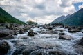 Clear river with rocks leads towards mountains