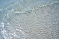 Clear ocean water over ripples in sand. Pure, crystalline water with sun reflections and soft wave. Royalty Free Stock Photo