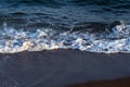 Clear sea water tide on dark volcanic beach. Relaxing sea wave surf over seashore.