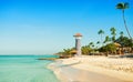 Clear sea, white sand, tropical palm trees and lighthouse on sandy shore Royalty Free Stock Photo