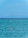 Clear sky over a blue sea. An orange buoy on the surface of the water. The horizon is above the water. Minimalistic landscape. Red Royalty Free Stock Photo