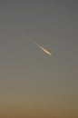 Clear sky after sunset at dusk and blue hour with airplane with contrails that glow like a comet or fireball with tail illuminated