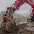 Clear Square Red excavator and barricade on a muddy mountain road viewed in winter Royalty Free Stock Photo