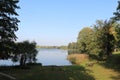 Clear sunny day and calm surface of Lake Birini with deciduous trees on the green shore Royalty Free Stock Photo