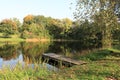 Clear sunny day and calm surface of Lake Birini with deciduous trees on the green shore Royalty Free Stock Photo