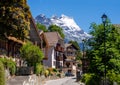 Street leading to the alpine community of Gryon Switzerland is framed by snow capped mountains in the distance