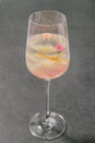 A clear sweet pink sparkling beverage decorated with fruit peels and small roses in a champagne glass.